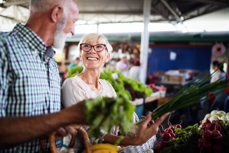 Only the best fruits and vegetables. Beautiful mature couple buying fresh food on marketの写真素材