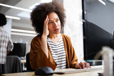 Overworked and frustrated young woman in front of computer in office