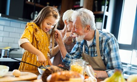 Happy senior couple having breakfast with their grandchildren at homeの写真素材