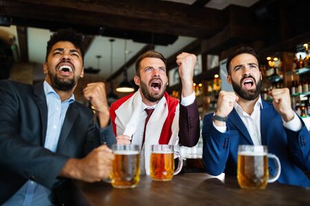 People, leisure, friendship, sport concept. Happy friends drinking beer, watching sport game at pubの写真素材