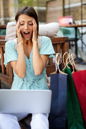 Happy excited woman reading good news on line in a laptop outdoorの写真素材