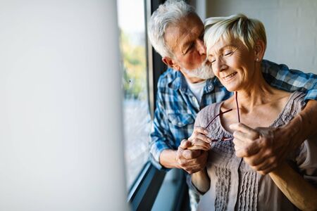 Happy senior couple in love hugging and bonding with true emotions at homeの写真素材