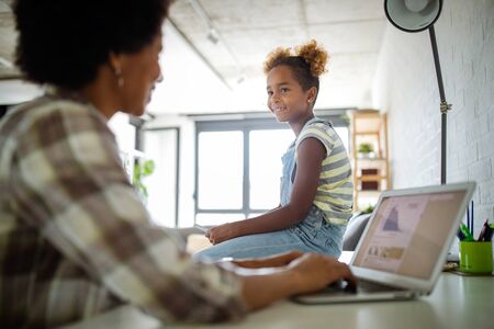 Happy family mother and child daughter at home working on the computerの写真素材