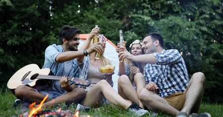 Happy friends playing music and enjoying bonfireの写真素材