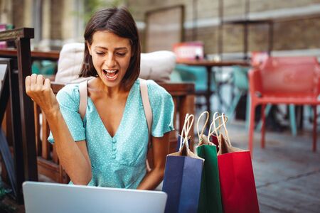 Happy excited woman reading good news on line in a laptop outdoorの写真素材