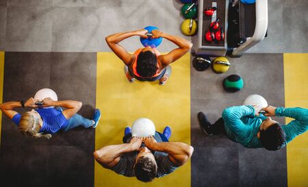 Young sporty people working out together with kettle bells in a gym.の写真素材