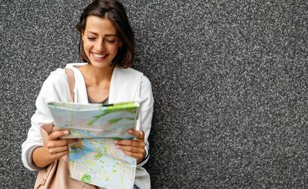 Happy young woman with a city map and a backpack smiling