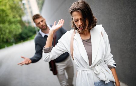 Sad young woman and man outdoor on street having relationship problemsの写真素材