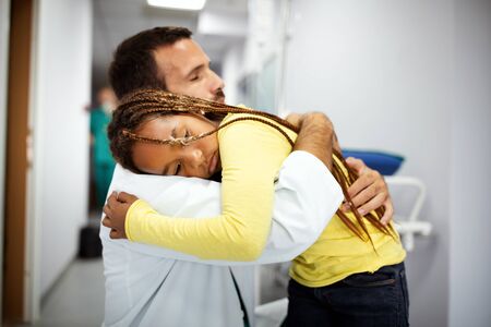 Doctor having conversation with sad little girl at the hospital. Doctor consoling childの写真素材