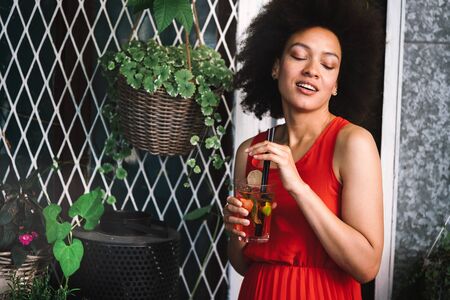 Beautiful happy black woman drinking healthy drink and smiling