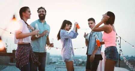Group of happy friends having party on rooftopの写真素材