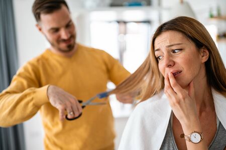 Man makes haircut to woman at home during quarantine.の写真素材