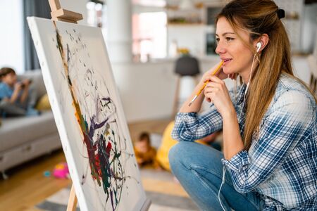 Happy young woman paints on canvas at homeの写真素材