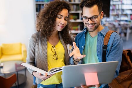 University students in cooperation at library. Group of young friends reading books.の写真素材