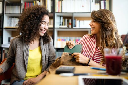 University students in cooperation at library. Group of young friends reading books.の写真素材