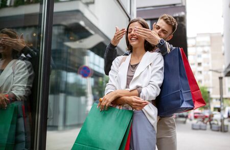 Beautiful young loving couple walking by the street with shopping bagsの写真素材