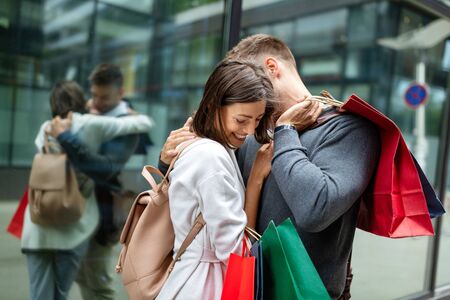 Cheerful successful happy young lovely couple with shopping bags traveling and laughingの写真素材