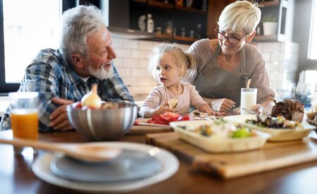 Happy grandparents with grandchildren making breakfast in kitchenの写真素材