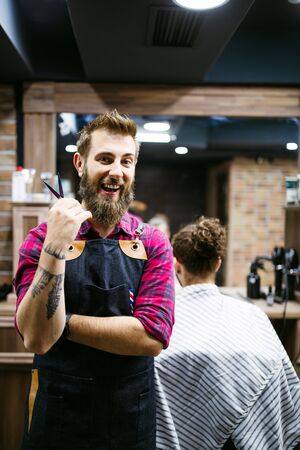 Barber man in an apron with arms crossed and happy in salonの写真素材