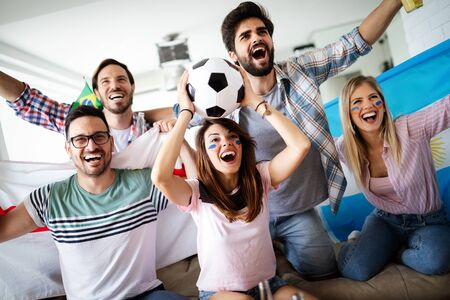 Young group of friends watching sport on televisionの写真素材
