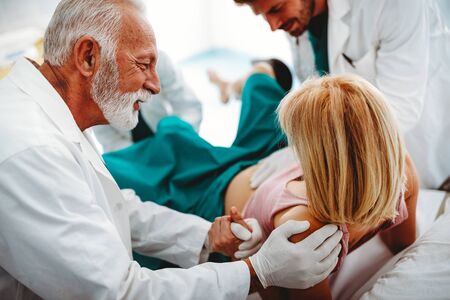 In the hospital woman in labor pushes to give birth, obstetricians assisting