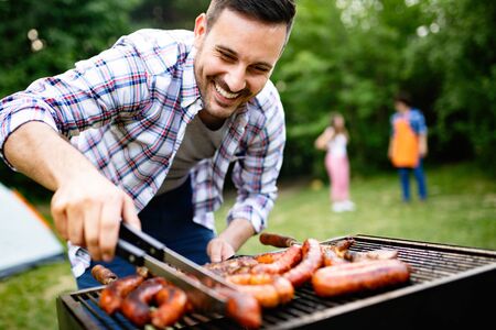 Handsome male preparing barbecue, grill outdoors for friendsの写真素材