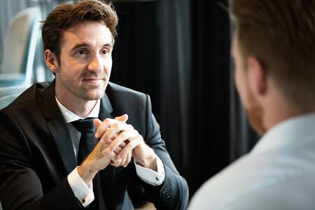 Successful businessman smiling while discussing with partner during meeting at coffee break