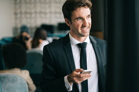 Young happy attractive business man using smartphone