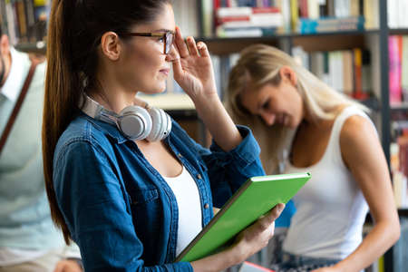 Education concept. University students preparing for exam, talking in libraryの写真素材