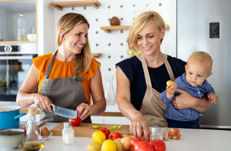 Happy lesbian couple with little daughter at homeの写真素材