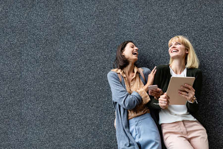 Two happy women are having fun together in the city. Technology, people fun concept