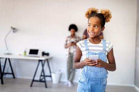 Smiling little girl playing with smartphone. Children, technology concept