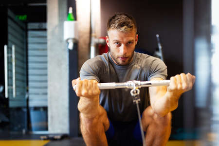 Fit happy man exercising at the gym on a machine