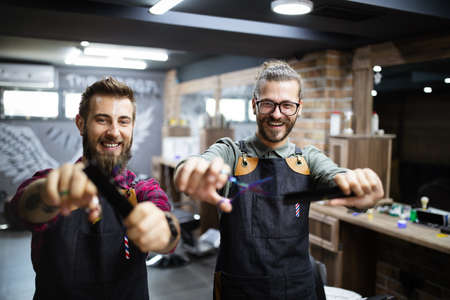 Portrait of young male barbers and hairdressers in barber shopの写真素材