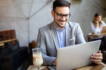 Portrait of a successful business man sitting at the cafe in front of a laptop.