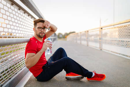 Running male adult taking a break. Tired exhausted man runner sweating after cardio workout.
