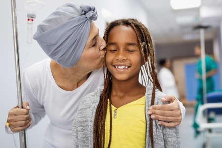 Sick woman with cancer hugging her young grandchild in hospital. Family support concept.の写真素材