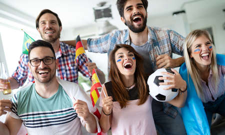 Soccer fans emotionally watching game in the living room.