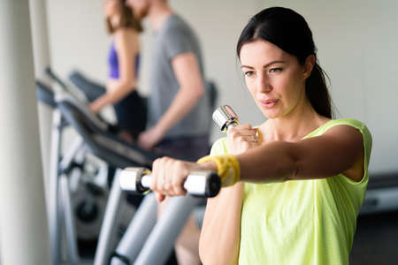 Portrait of a young happy fit woman with dumbbells