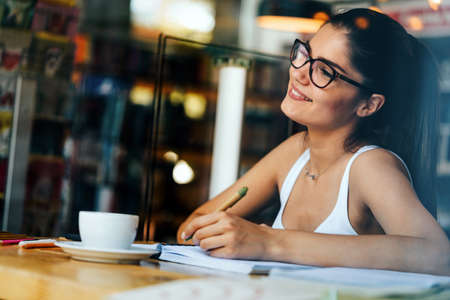 Beautiful young student with lots of books, studying or preparing for examsの写真素材