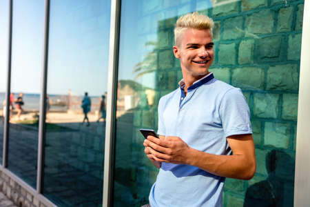Outdoor portrait of modern young man with mobile phone in the streetの写真素材