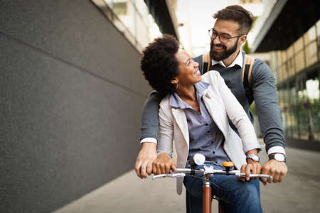 Happy business couple riding bike through city and having funの写真素材
