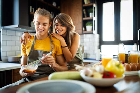 Young happy couple is enjoying and preparing healthy meal in their kitchenの写真素材