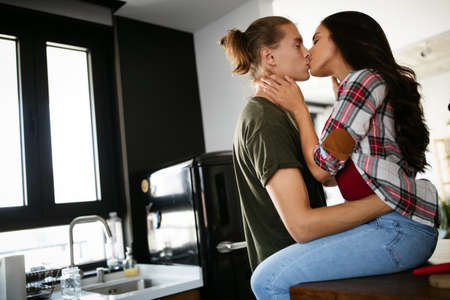 Beautiful young passionate couple is smiling and hugging before having sex at homeの写真素材