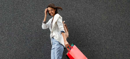 Very happy beautiful young woman in casual clothing with shopping bags