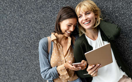Group of young business people holding different digital devices outdoor