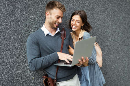 Happy young couple using laptop outdoor. Travel, business, people fun concept