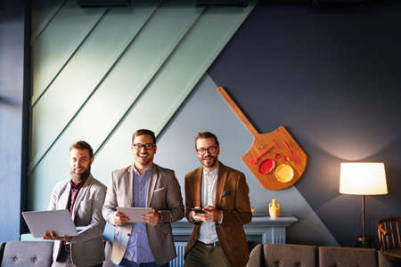 Group of confident happy business people holding digital devices