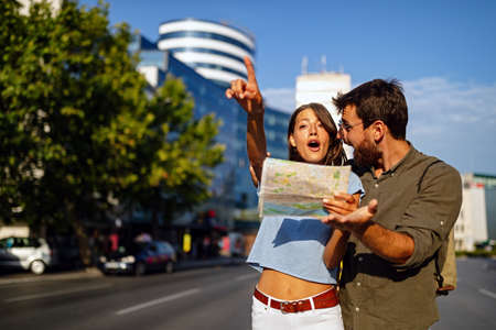Happy couple on vacation sightseeing city with map