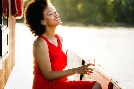 Lifestyle fashion portrait of stunning woman resting outdoor. Glass in hand. Drinking champagne.の写真素材